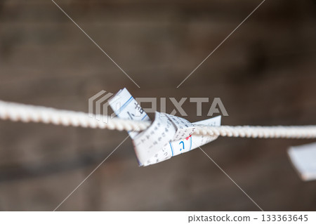 Close-up shots capture traditional white paper slips carrying wishes, tied to ropes. Close-up shots capture traditional white paper slips carrying wishes, tied to ropes. 133363645