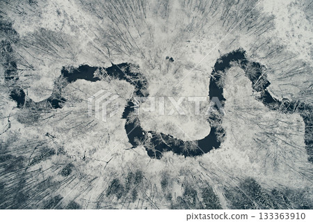 Aerial view of the winding river against the backdrop of snowy fields and winter forest. Meander from the top Aerial view of the winding river against the backdrop of snowy fields and winter forest. Meander from the top 133363910