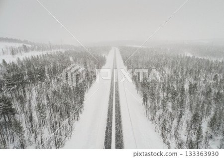 Aerial view of the highway against the backdrop of a winter forest in cloudy gray weather Aerial view of the highway against the backdrop of a winter forest in cloudy gray weather 133363930
