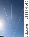 Contrails from aircraft create dynamic patterns in the clear blue sky, with sunlight illuminating the scene, showcasing the beauty of aviation and nature combined 133364160