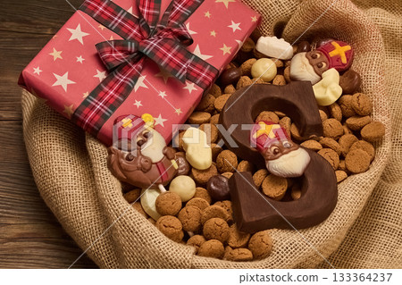 Festive Sinterklaas Display. A burlap basket with chocolate letters, Sinterklaas figures, and a starry gift box 133364237