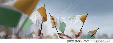 Cote dIvoire flags in their hands on a blurred urban background 133365277