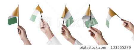 The Cote dIvoire flag in hand in different angles on a white background 133365279