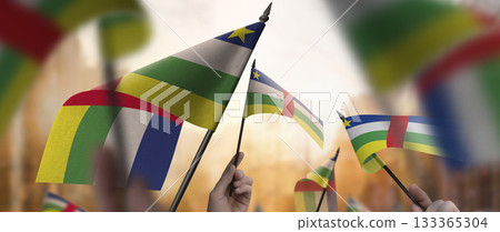 Central African Republic flags in their hands on a blurred urban background Central African Republic flags in their hands on a blurred urban background 133365304