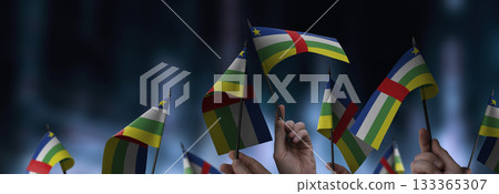 Central African Republic flags in their hands on a blurred urban background 133365307