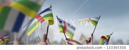 Central African Republic flags in their hands on a blurred urban background 133365308