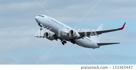 Airplane take off on the blue sky, with white clouds. Aircraft flying on sky background. White passenger jet plane in the blue sky. Low angle view of Airplane flying under blue sky, with white clouds 133365447