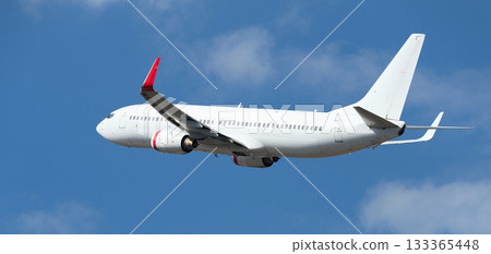 Airplane take off on the blue sky, with white clouds. Aircraft flying on sky background. White passenger jet plane in the blue sky. Low angle view of Airplane flying under blue sky, with white clouds Airplane take off on the blue sky, with white clouds. Aircraft flying on sky background. White passenger jet plane in the blue sky. Low angle view of Airplane flying under blue sky, with white clouds 133365448