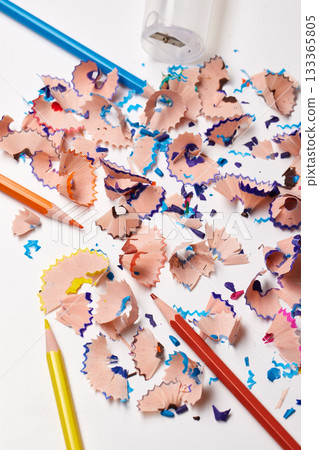 Colorful pencil shavings with drawing pencils and a sharpener on a white background 133365805