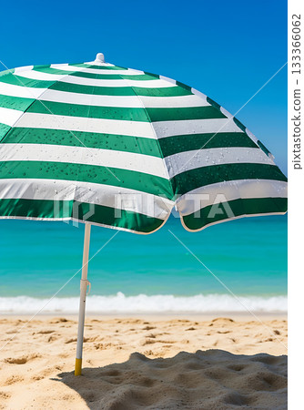 Green and white striped beach umbrella on a sunny day at the shore 133366062
