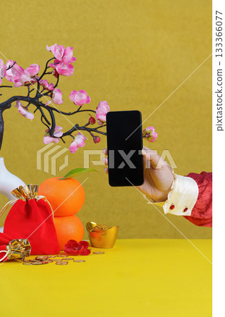 Lunar New Year Celebration. Hand holding smartphone with festive decorations. 133366077