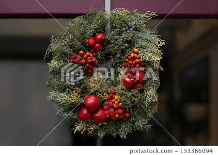 A Christmas wreath of red berries hanging on a door 133366094