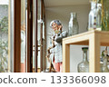 A 75-year-old gray-haired woman looks out the window 133366098