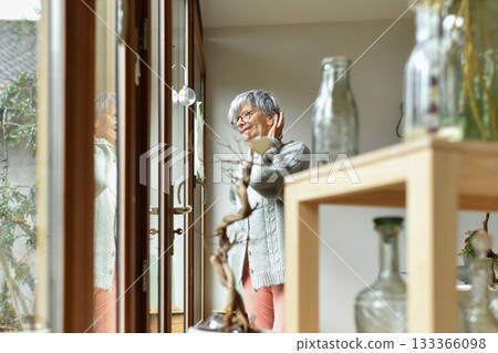 A 75-year-old gray-haired woman looks out the window A 75-year-old gray-haired woman looks out the window 133366098