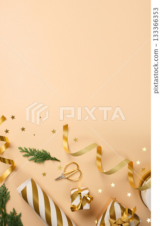 Items for Christmas gift wrapping. Golden and white striped wrapping paper, ribbon, scissors on beige backdrop. Copy space. Items for Christmas gift wrapping. Golden and white striped wrapping paper, ribbon, scissors on beige backdrop. Copy space. 133366353
