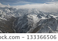 Snow-covered mountain range with dramatic peaks and valleys under clouds 133366506