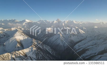 Snow-capped mountain range under clear blue sky with dramatic peaks 133366511