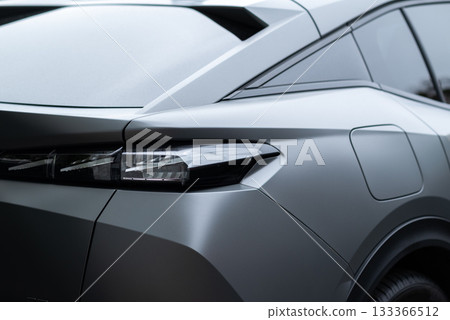 Modern car rear section closeup with sleek LED taillight design and matte gray finish. 133366512