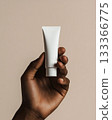 Close up of a woman's dark skin holding a glass of water and a tube of skin care cream,  trying the product with her finger, soft liquid texture, emphasis on skin care and health,  medical and cosmeti 133366775