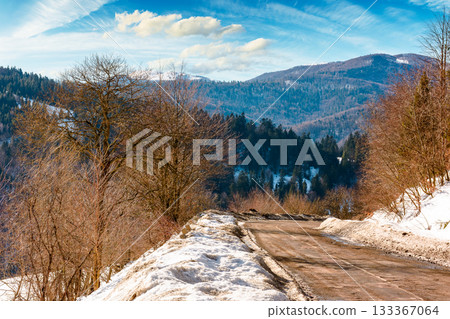 country road winding through winter landscape under blue sky. great bereznyi district of carpathian mountains on a sunny day. scenic view of uzhanian pass. travel background with snow covered slopes country road winding through winter landscape under blue sky. great bereznyi district of carpathian mountains on a sunny day. scenic view of uzhanian pass. travel background with snow covered slopes 133367064