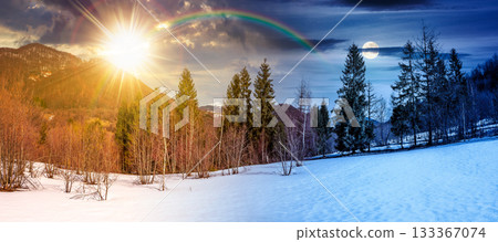 snow covered slope with forest on spring equinox. day and night time change concept. stunning panorama of mountainous countryside landscape with sun and moon. duality and transition template 133367074