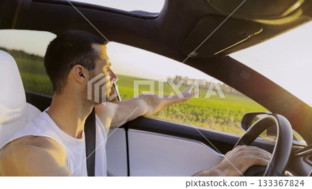 Profile of young handsome man driving a modern electric car with sunlight at background. Young male driver riding on electrical vehicle at countryside. Concept of journey and trip. Close up Profile of young handsome man driving a modern electric car with sunlight at background. Young male driver riding on electrical vehicle at countryside. Concept of journey and trip. Close up 133367824