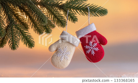 Christmas felt mittens with snowflake embroidery hanging on fir branch, cozy handmade wool decorations with warm sunset background Christmas felt mittens with snowflake embroidery hanging on fir branch, cozy handmade wool decorations with warm sunset background 133368165