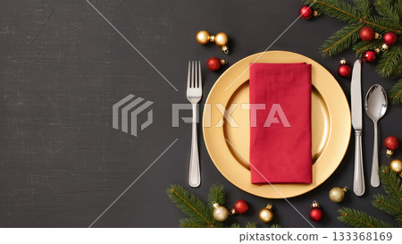 Christmas table setting with golden plate, red napkin, silver cutlery, fir branches, and baubles on dark wooden background. Elegant holiday arrangement. Christmas table setting with golden plate, red napkin, silver cutlery, fir branches, and baubles on dark wooden background. Elegant holiday arrangement. 133368169