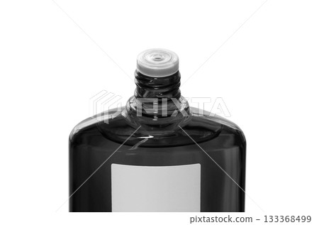 A black translucent bottle of hair growth product with the screw cap open 133368499