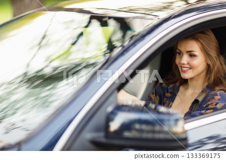 Happy woman driver at car smiling. Cute young happy brunette female driving car vehicle 133369175