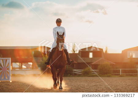 Woman rider jockey in helmet and white uniform preparing horse racing 133369217