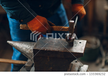 Blacksmith forges and making arrow metal detail with hammer and anvil at forge. Blacksmith forges and making arrow metal detail with hammer and anvil at forge. 133369232