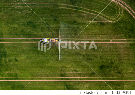 aerial view of the tractor spraying the chemicals on the large green field 133369391