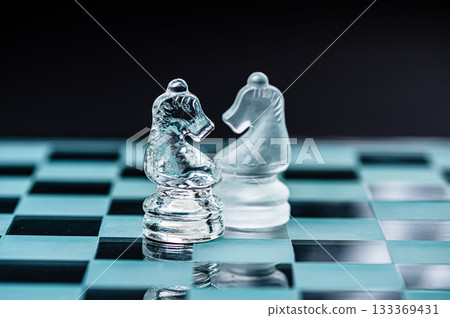 two opponent glass chess knights on a glass chess board, black background 133369431