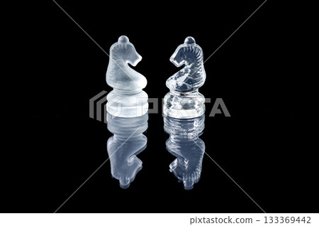 two opponent glass chess knights with reflection isolated on a black glass background 133369442