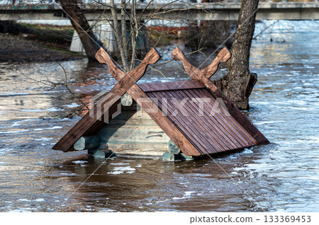 to the roof flooded in spring floods bird house - feeder in the river near the pedestrian bridge to the roof flooded in spring floods bird house - feeder in the river near the pedestrian bridge 133369453
