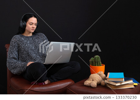 focused young freelance woman sitting with laptop and headphones, have business meeting via video call 133370230