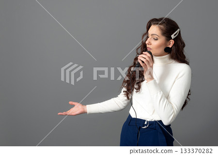attractive female conference speaker during presentation, holds microphone and makes some gestures 133370282