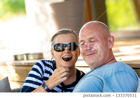 happy married couple feeding one another with ripe cherries, engaging outdoor recreation and flirting 133370531