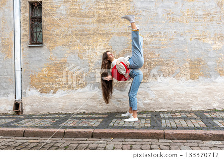 funny teenager carrying her best friend piggyback on the street at the old wall, positive emotions funny teenager carrying her best friend piggyback on the street at the old wall, positive emotions 133370712