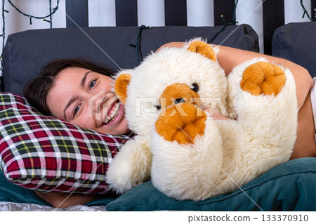attractive smiling happy young woman hugging her teddy bear at bedroom attractive smiling happy young woman hugging her teddy bear at bedroom 133370910