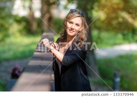 fashion portrait of a stylish nice blonde female in sunglasses leaning on a railing of pedestrian bridge 133370946
