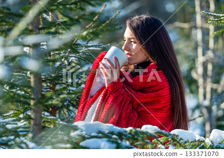 beautiful woman with a red plaid on her shoulder and a cup of tea in winter wood, winter portrait 133371070