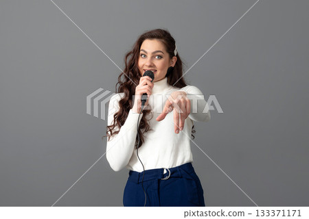 attractive female conference speaker during presentation, holds microphone and makes some gestures 133371171