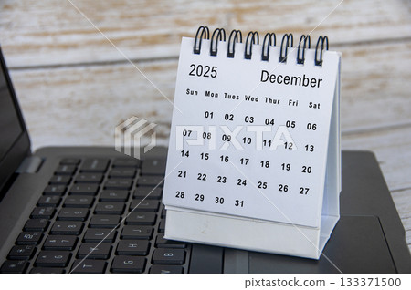 White calendar of December 2025 calendar on top of laptop. Year end concept. White calendar of December 2025 calendar on top of laptop. Year end concept. 133371500