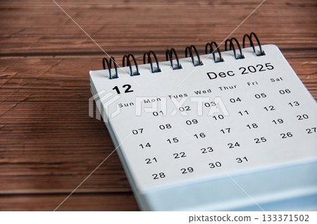 Side view of December 2025 calendar on wooden table. Year end concept. Side view of December 2025 calendar on wooden table. Year end concept. 133371502