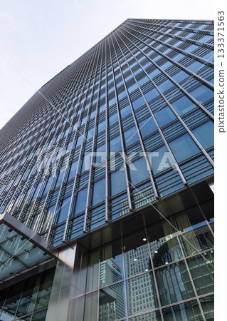 Modern glass skyscraper with reflective facade in downtown business district Modern glass skyscraper with reflective facade in downtown business district 133371563