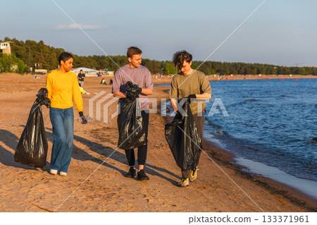 Earth day. Volunteers activists team collects garbage cleaning of beach coastal zone. Woman mans with trash in garbage bag on ocean shore. Environmental conservation coastal zone cleaning 133371961