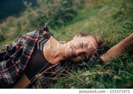content woman basking outside, delighted woman reclining comfortably in verdant meadow with radiant content woman basking outside, delighted woman reclining comfortably in verdant meadow with radiant 133371973