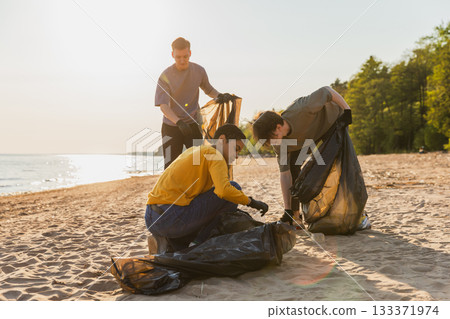 Earth day. Volunteers activists collects garbage cleaning of beach coastal zone. Woman and mans puts plastic trash in garbage bag on ocean shore. Environmental conservation coastal zone cleaning Earth day. Volunteers activists collects garbage cleaning of beach coastal zone. Woman and mans puts plastic trash in garbage bag on ocean shore. Environmental conservation coastal zone cleaning 133371974